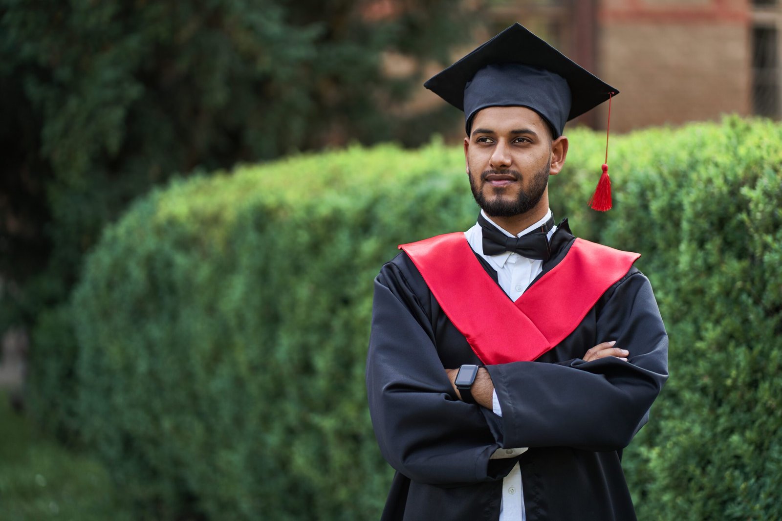 Home 4 serious indian graduate graduation robe with crossed arms looking forward scaled